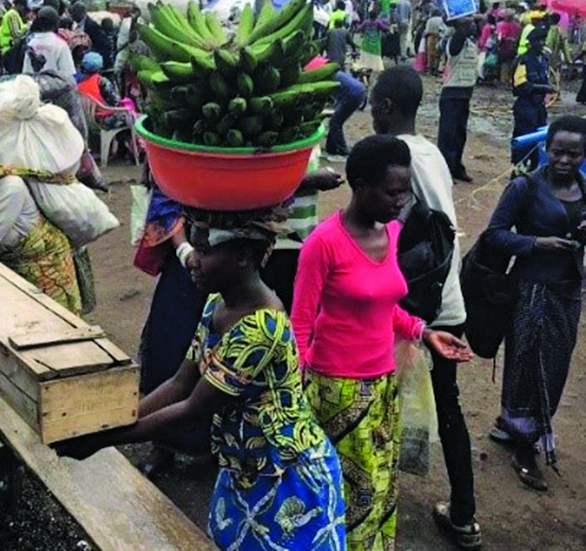 Woman from Rwanda carrying plantains washes her hands at a handwashing station