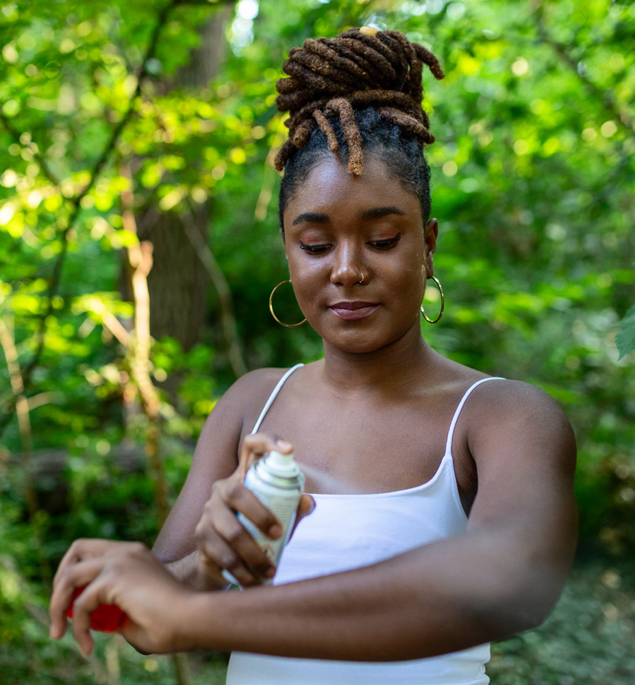 Woman applying insect repellent against mosquito and tick on her arms during hike in nature.