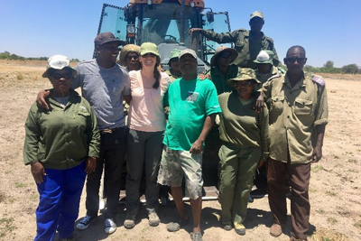 Team of people in a group in front of large machinery