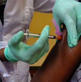 doctor with gloved hands giving a vaccine to someone's arm