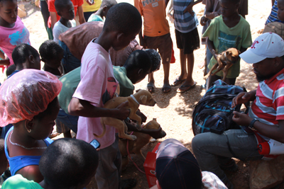 Man with a bag of medical equipment is surrounded by children with their dogs