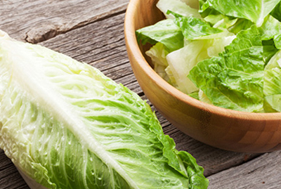 head of romaine lettuce next to a bowl full of chopped romaine lettuce