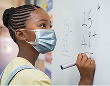 A young girl doing a math problem at a white board