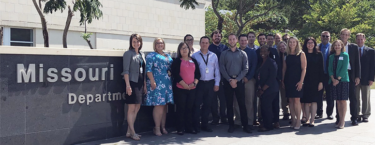 Group shot of 21 people standing in front of the Missouri Department of Health and Senior Services building.