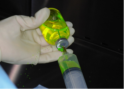 gloved hand holding vial of medication