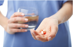 someone holding medicine and a glass of water