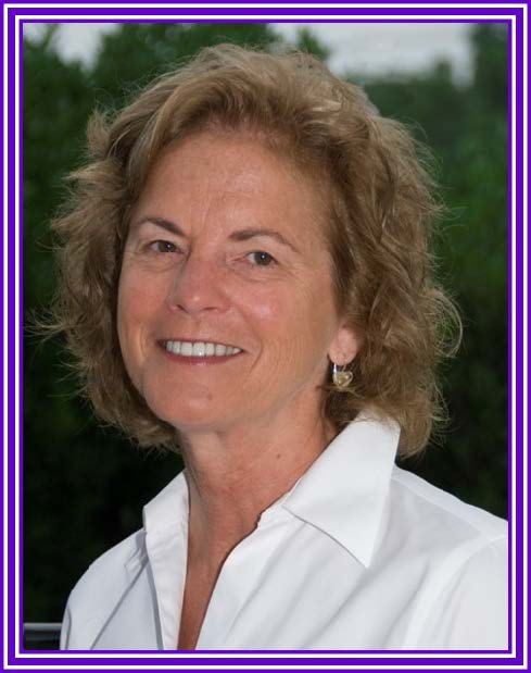 Portrait: Dr. Nancy Stout, wearing a white collared shirt, smiling and looking into the camera.