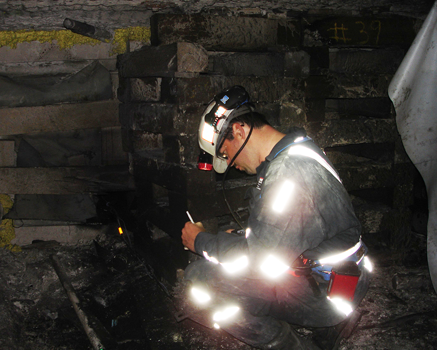 A photo of Steve Sawyer kneeling to perform an investigation after an underground mine explosion.