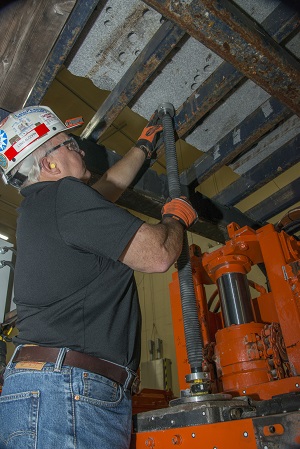 Photograph of researcher performing laboratory testing of the new collapsible drill still enclosure prototype.