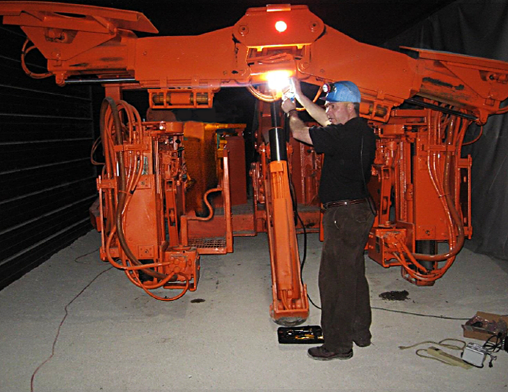 A man attaches an LED area light to a roof bolter