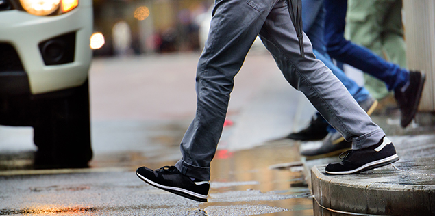 man walking over puddle in the rain