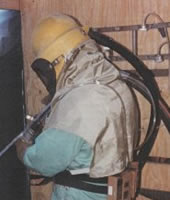 a worker wearing protective equipment while abrasive blasting