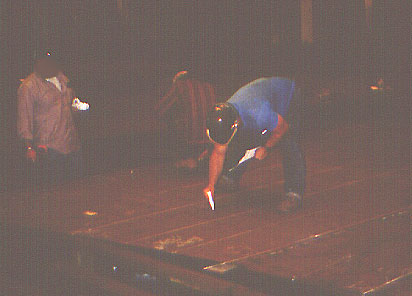 Worker bending over to mark the plate at floor level using chalk or paint markers