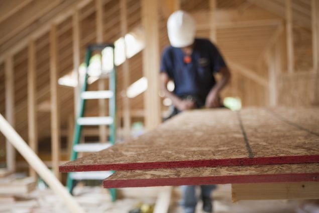 Construction worker measuring and cutting particle board. Particle board is known to emit formaldehyde gas.