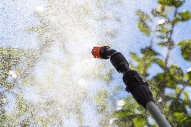 Working spraying fruit trees to protect against insects.