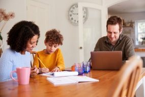 A family sits at a table while a child works on a written project