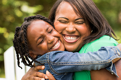 mother hugging daughter tightly while smiling