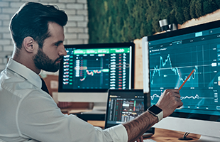 White business casual male pointing at line graph on computer screen with a pencil