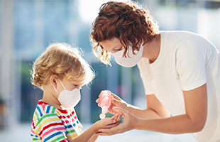 woman applying hand sanitizer on child