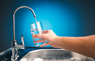 drinking glass under running faucet