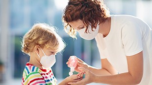 woman applying hand sanitizer on child