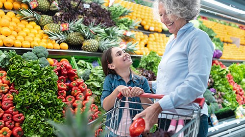 Grandmother and child shopping for fruits and vegetables in grocery.