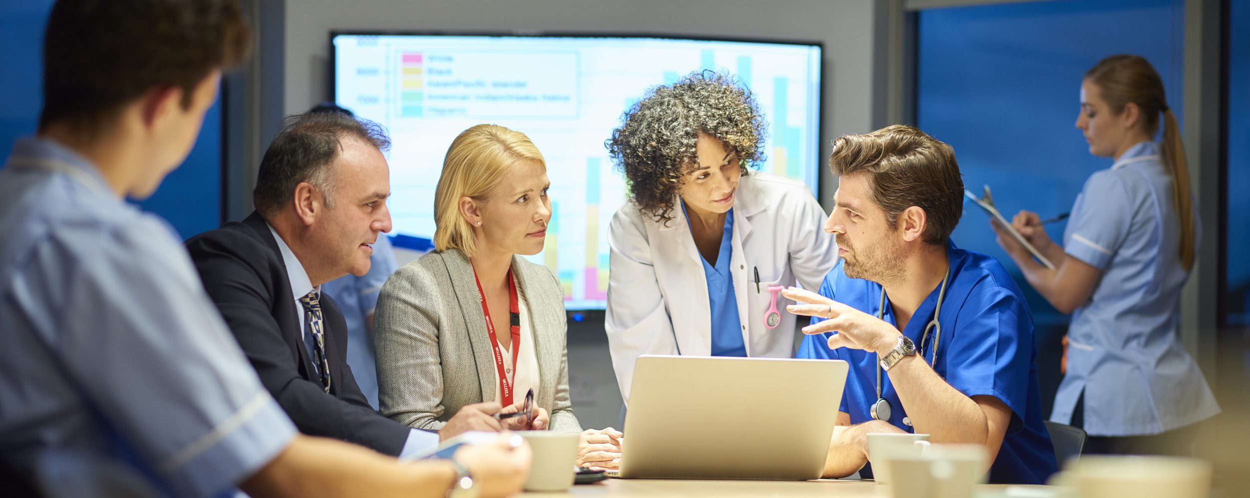 a group of healthcare professional and business people meet around a conference table