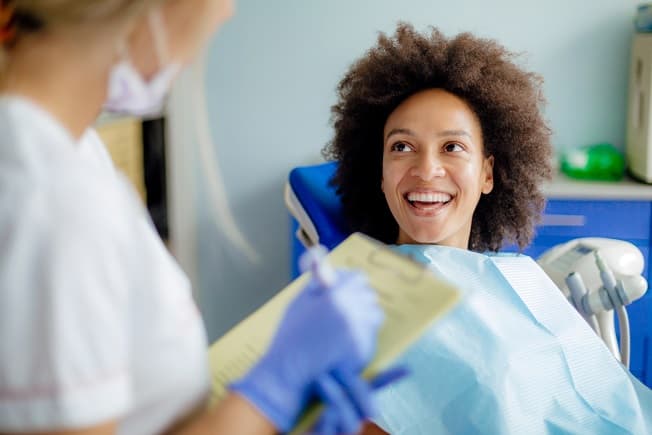 Woman in a dental chair speaking to a dentist