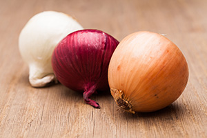 Various onions on a wooden table.