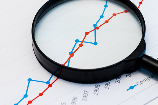 magnifying glass sitting on paper with a line graph