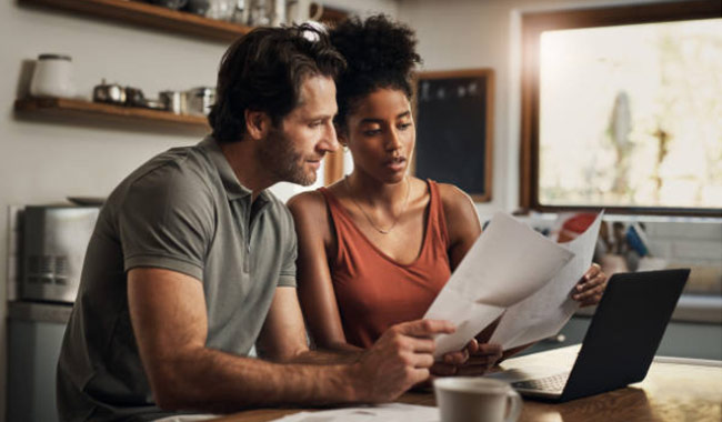 Man and woman reviewing paperwork in front of laptop