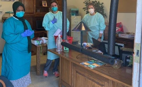 Three women in an office in masks and gloves