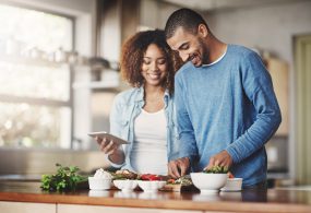 Photo of two people cooking together.