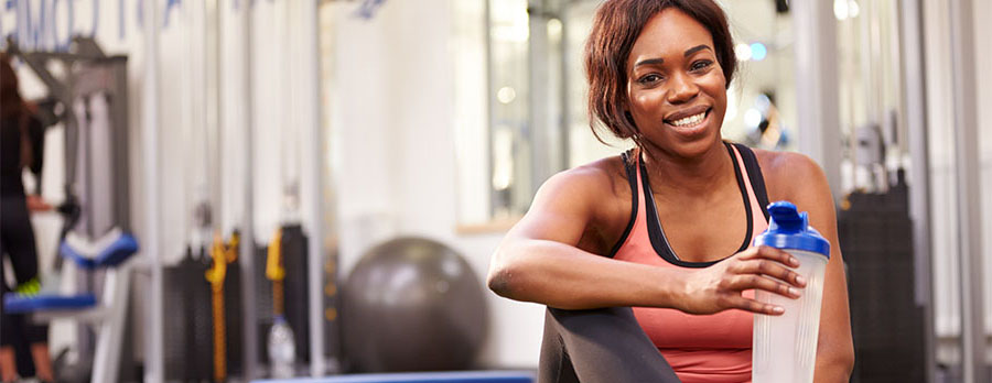 Young woman drinking water in a gym.